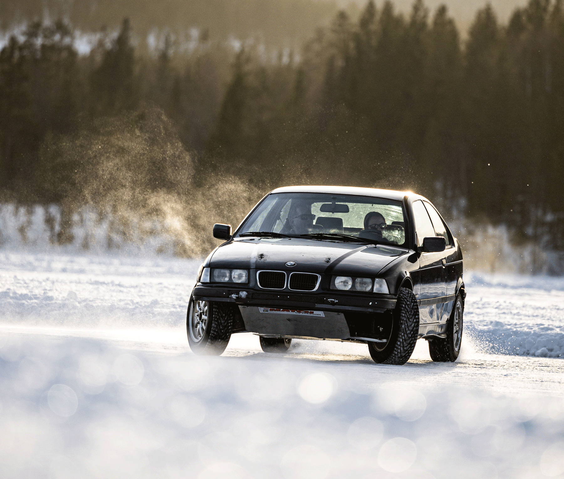 Zwarte BMW driftauto op besneeuwd ijs met spikereifen