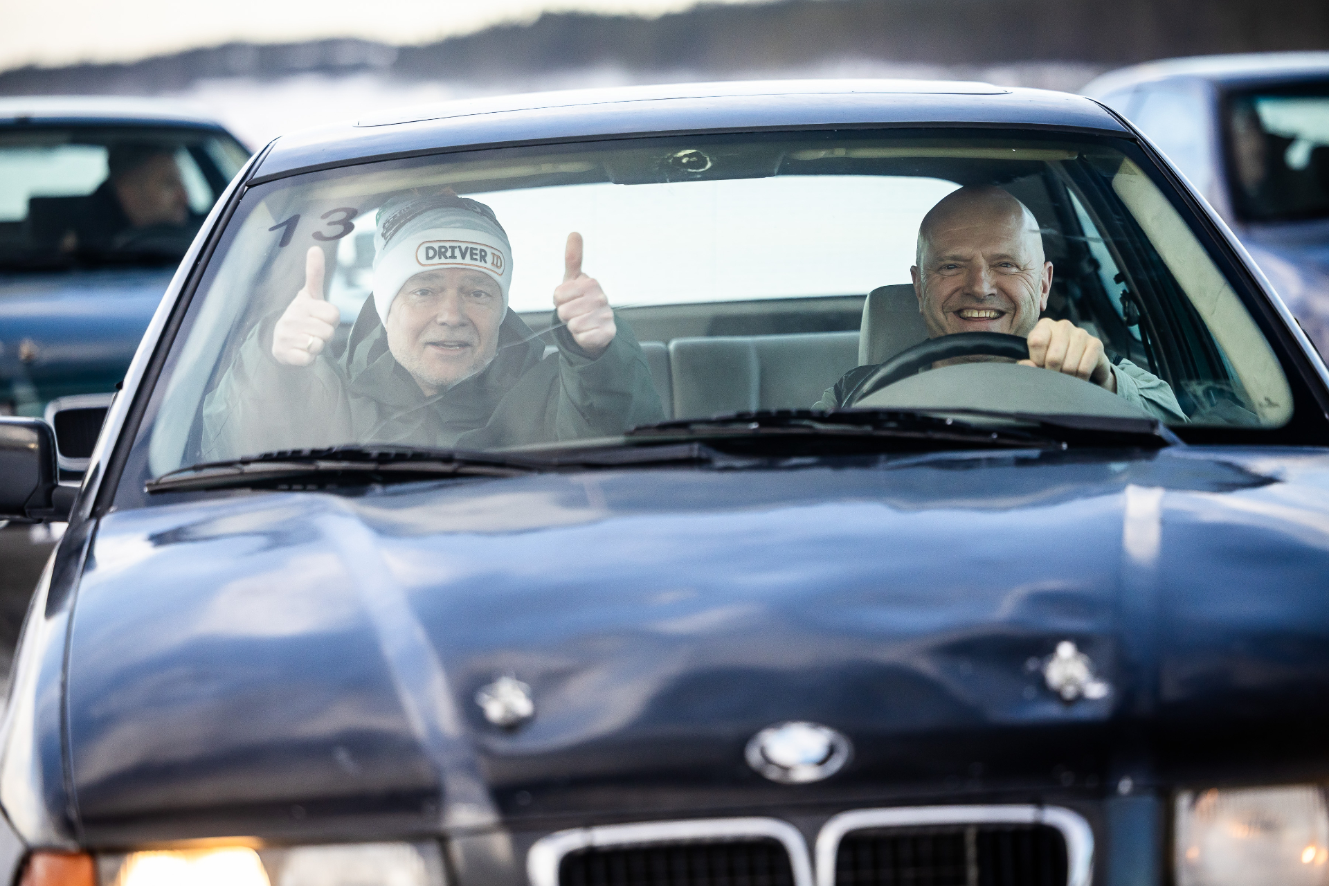 Deelnemers met duimen omhoog in BMW driftauto