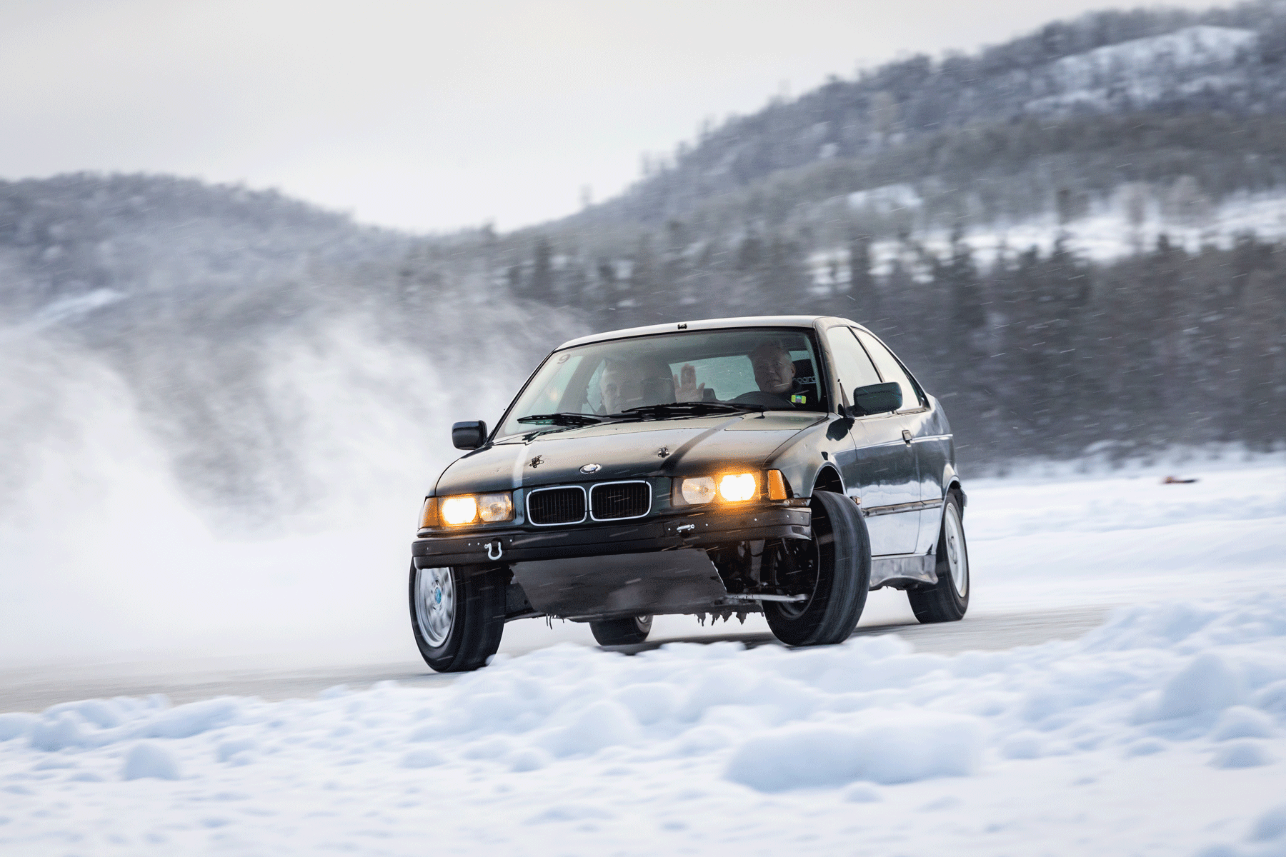 Gouden BMW driftauto op besneeuwd ijsmeer in Zweden