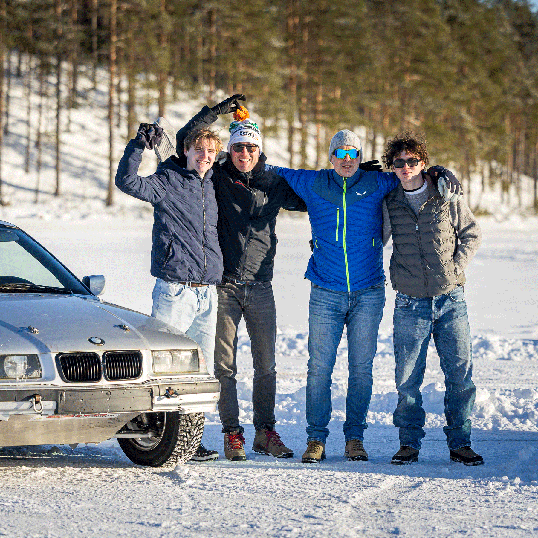 Groepsfoto met deelnemers naast een zilveren BMW op het ijs in Zweden
